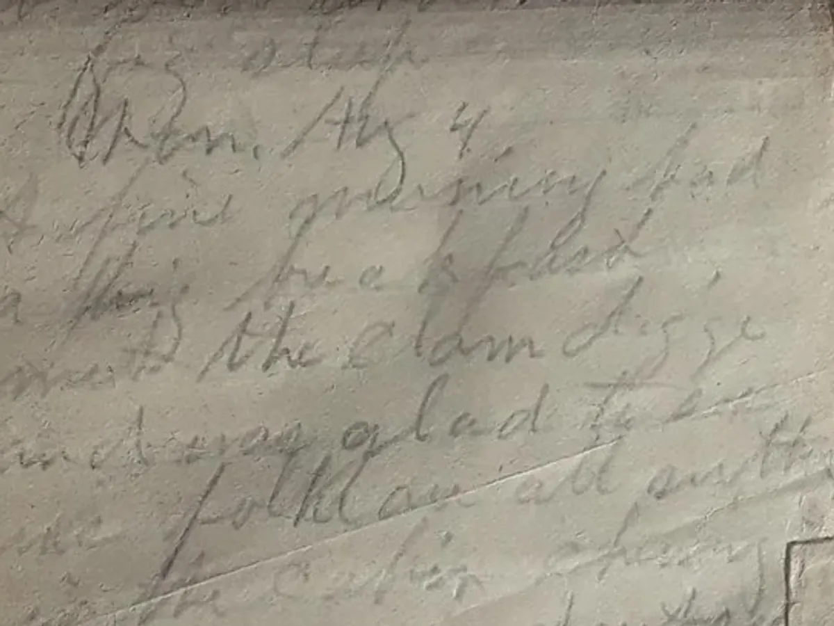 Close-up of a handwritten letter in pencil, the writing faded almost to the tone of the paper